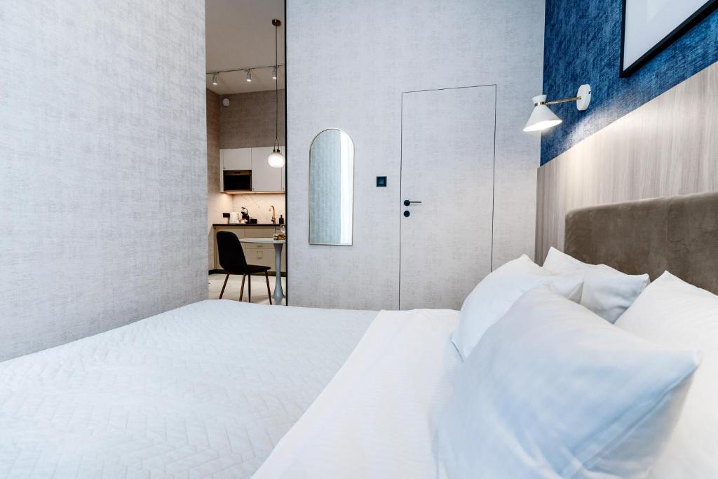 a bedroom with a white bed and a kitchen at Apartament UKIEL PARK 39 przy Plaży Miejskiej - klimatyzacja,free parking,FV in Olsztyn