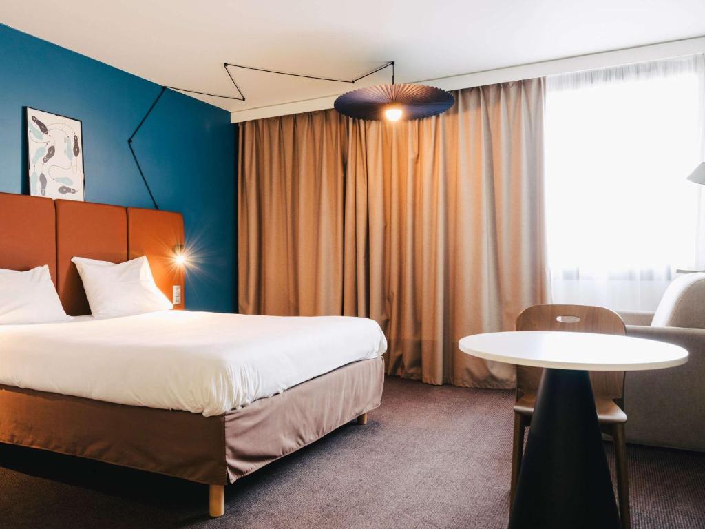 une chambre d'hôtel avec un lit et une table dans l'établissement Ibis Rouen Centre Rive Gauche Mermoz, à Rouen