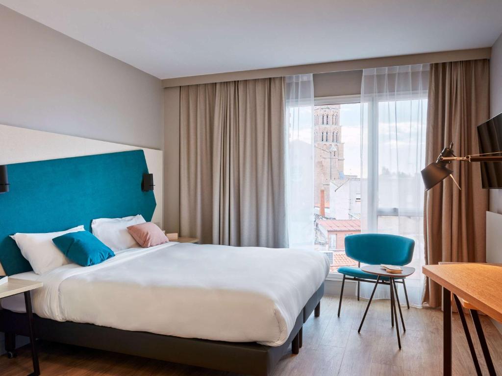 トゥールーズにあるAparthotel Adagio Original Toulouse Centre La Graveのベッドと大きな窓が備わるホテルルームです。