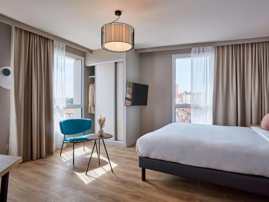 - une chambre avec un lit et une chaise bleue dans l'établissement Aparthotel Adagio Original Toulouse Centre La Grave, à Toulouse