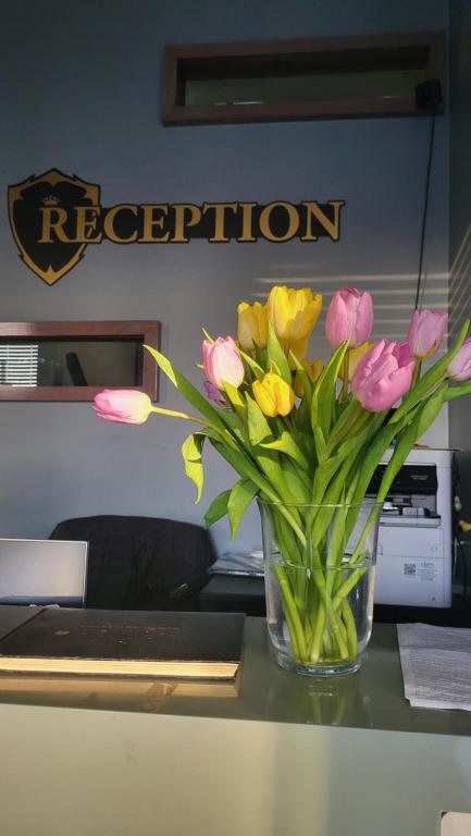 wazon wypełniony różowymi i żółtymi kwiatami na stole w obiekcie Bennetts Hotel w mieście Long Eaton