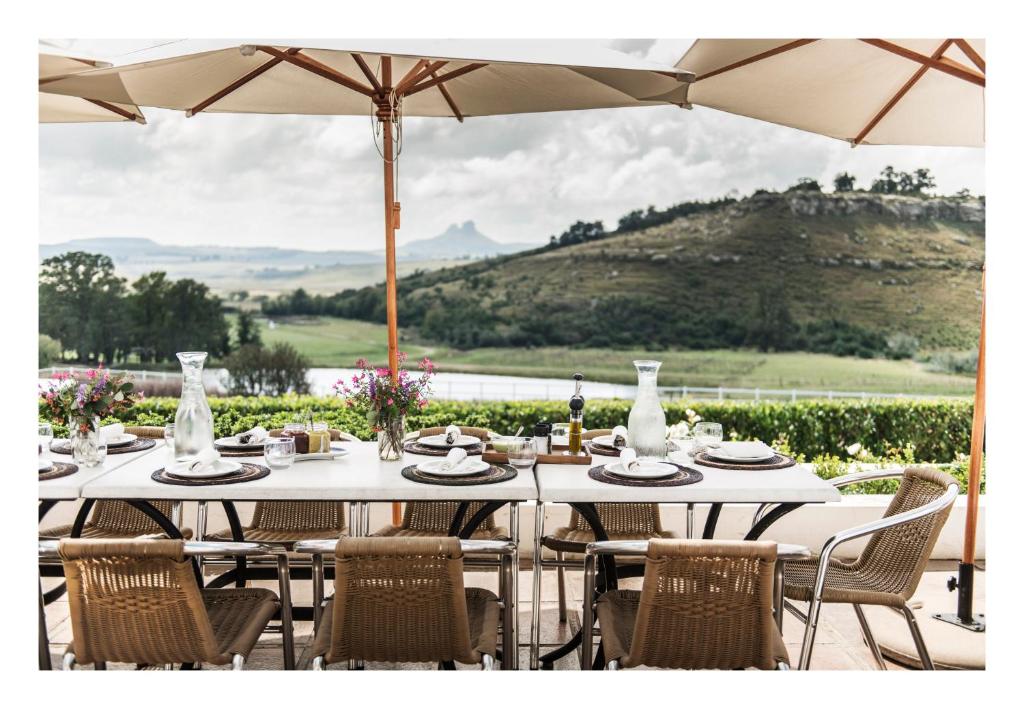 un tavolo bianco con sedie e ombrellone di Oaklands Farm Stay a Van Reenen