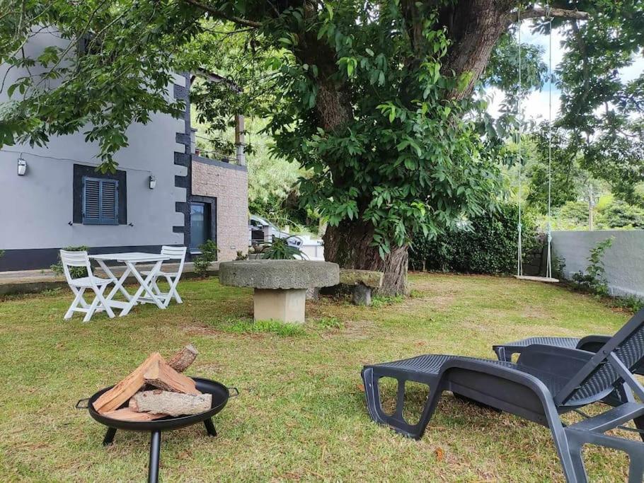 a backyard with a fire pit and a table and chairs at Castanheiro's Place in Ponta Delgada