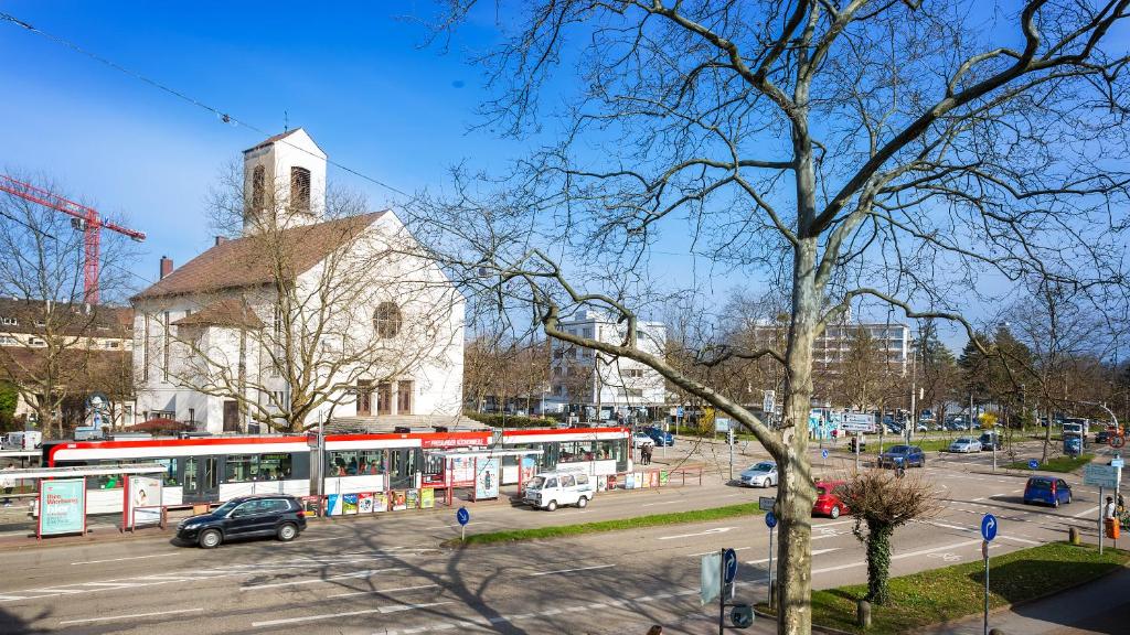 une rue avec une église blanche et un bus dans l'établissement Apartments an der Uniklinik, à Fribourg-en-Brisgau