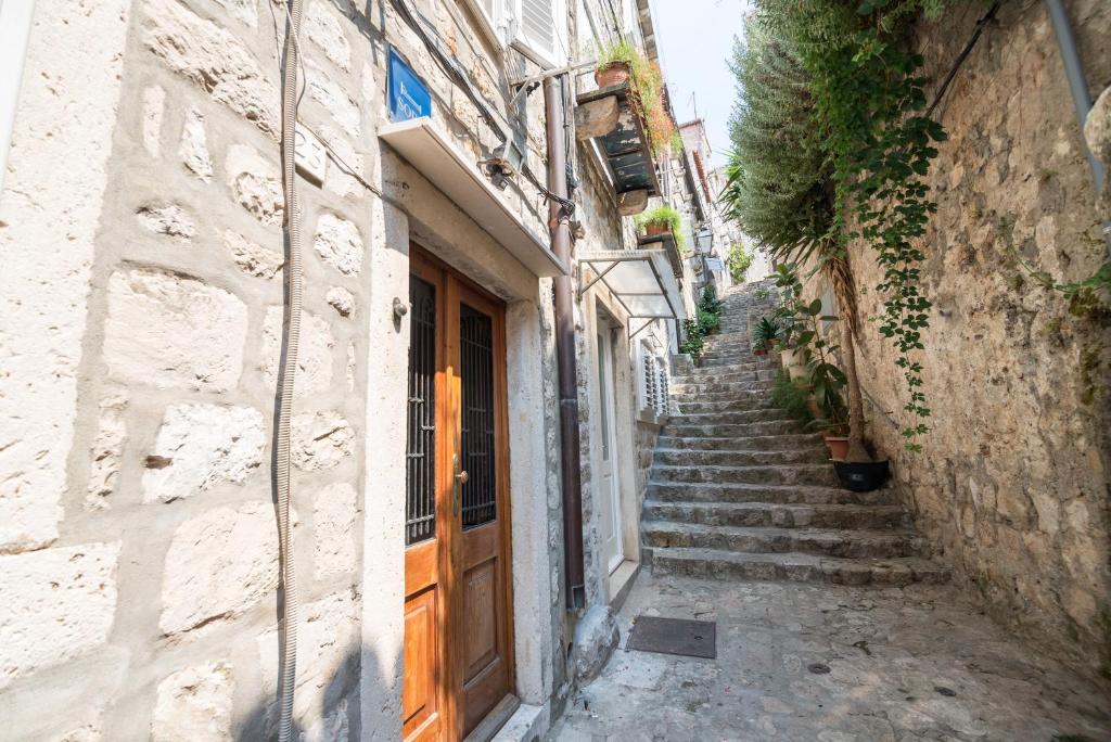 an alley with stairs leading up to a building with a wooden door at Rooms Ane Old Town in Dubrovnik
