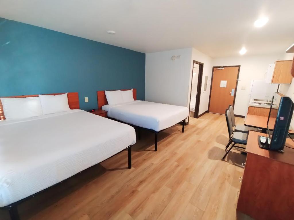 a room with two beds and a desk and a chair at WoodSpring Suites Asheville in Asheville