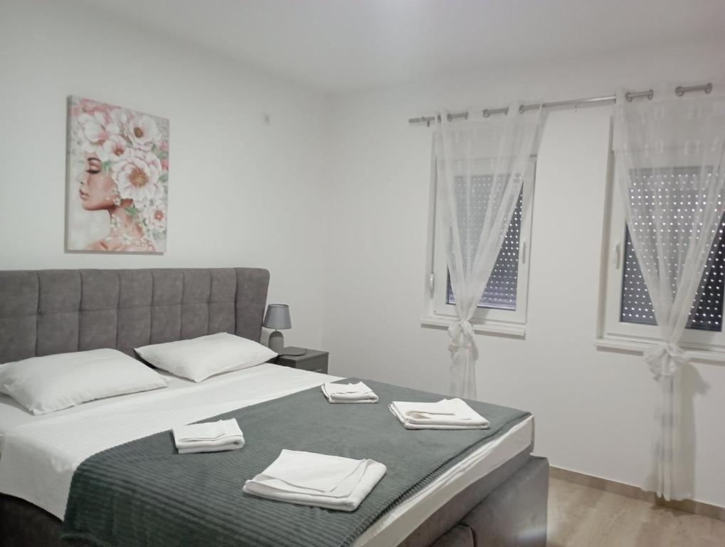 Apartmani Marija في فردنيك: غرفة نوم بيضاء مع سرير عليه مناشف