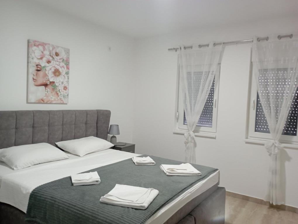 a white bedroom with a bed with towels on it at Apartmani Marija in Vrdnik