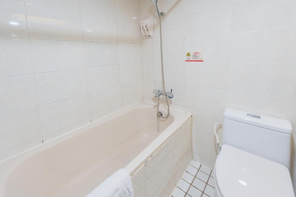 a white bathroom with a toilet and a bath tub at Oriental Hotel in Tainan