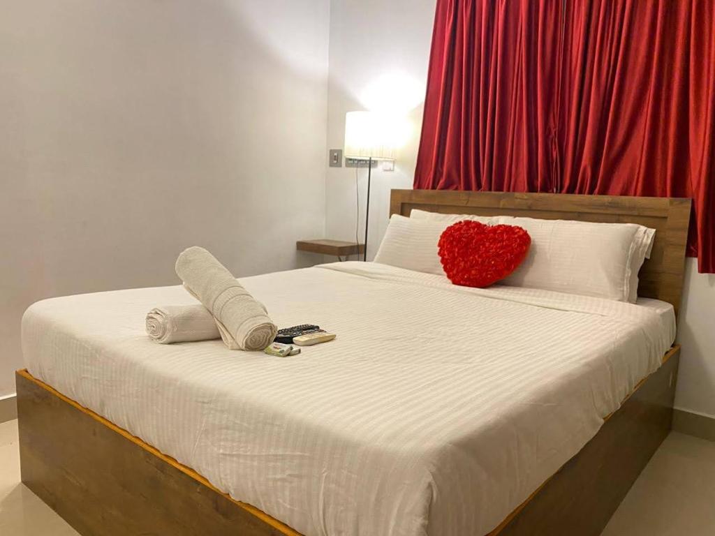 uma cama com uma almofada de coração vermelho e toalhas em La Paradise Residency em Pondicherry