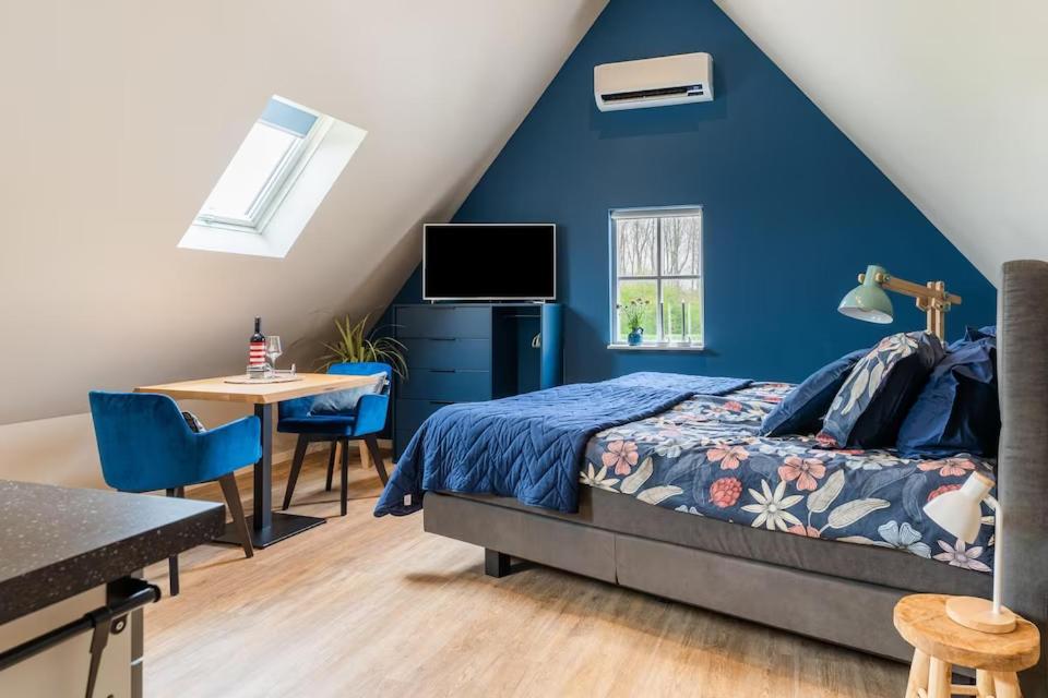 een slaapkamer met een blauwe muur en een bed en een tafel bij B&B Studio/Appartement Bij Zee in Stellendam