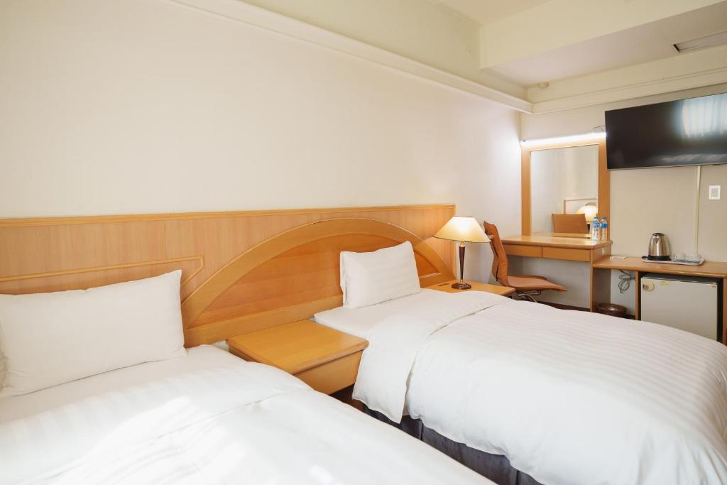 a hotel room with two beds and a television at Oriental Hotel in Tainan