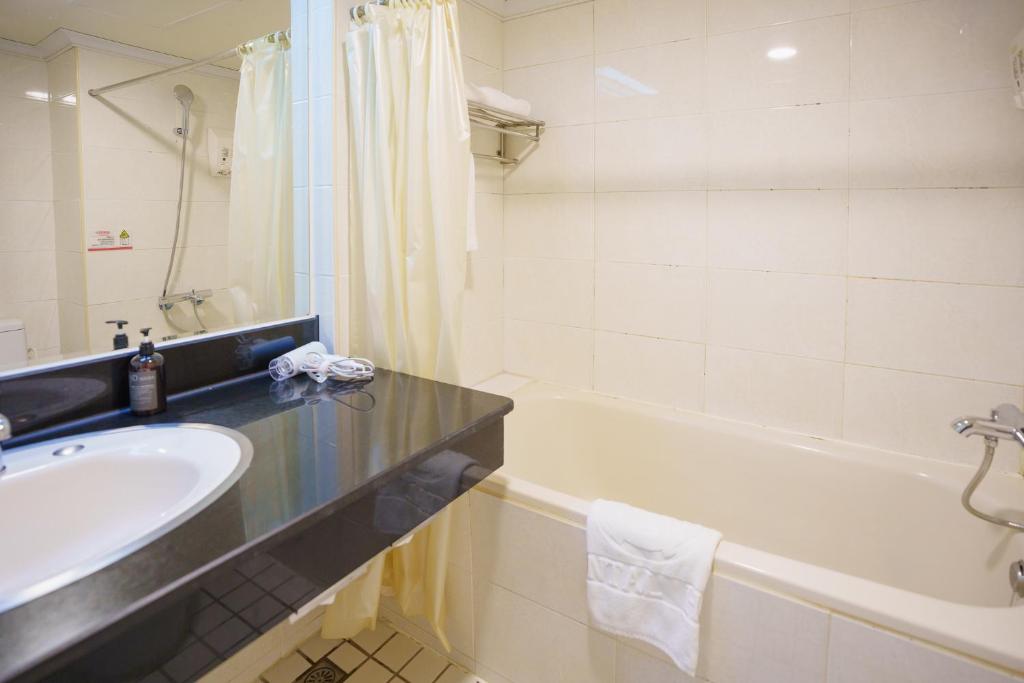 a bathroom with a sink and a bath tub at Oriental Hotel in Tainan