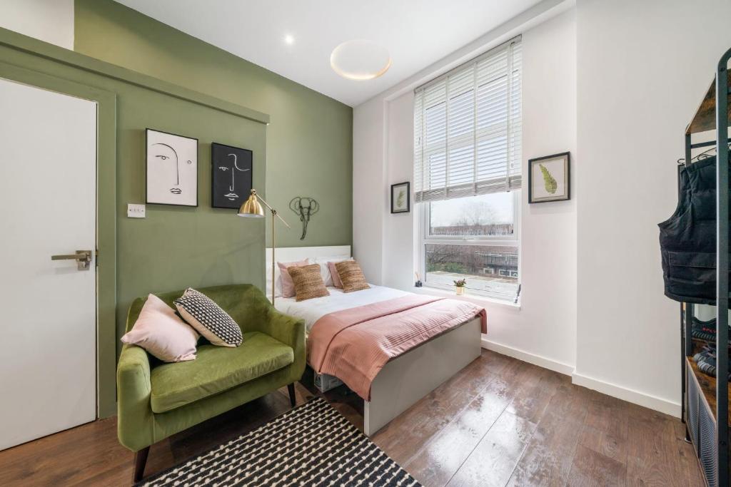 een slaapkamer met een bed en een groene stoel bij Stunning studio flats in Penge in Sydenham