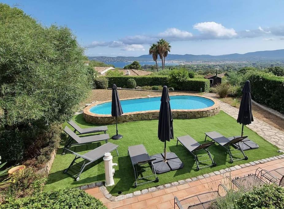 a swimming pool with chairs and umbrellas and a pool at LE CLOS BUCCI - Golfe de Saint-Tropez - Les hauts de Grimaud, villa avec vue exceptionnelle in Grimaud