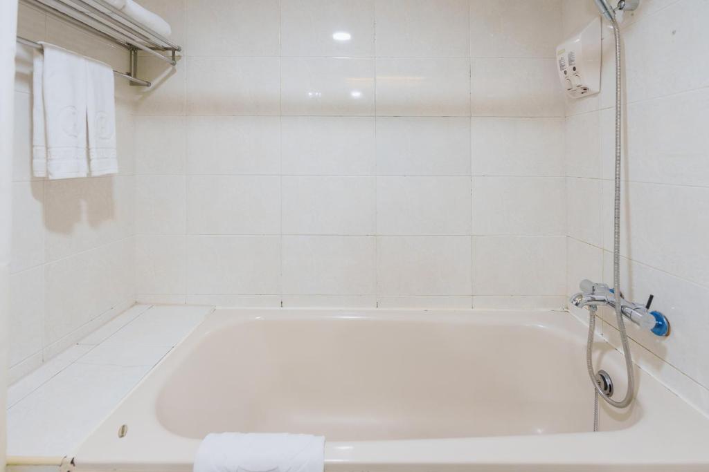 a white bath tub in a white tiled bathroom at Oriental Hotel in Tainan