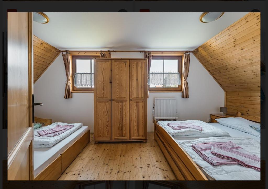 two beds in a room with two windows at Chatyliptov-Drevenice Liptovský Trnovec v srdci LIPTOVA in Liptovský Trnovec