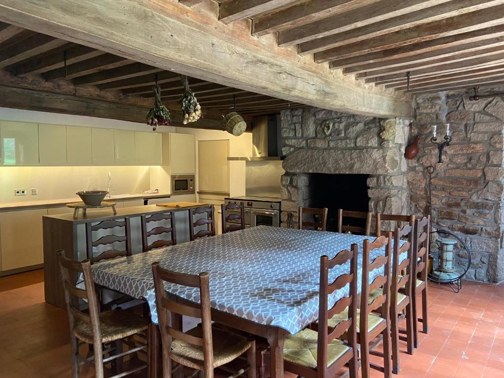 a dining room with a table and chairs and a kitchen at Ancienne Auberge des Brizards - Morvan (14 personnes) in Quarré-les-Tombes