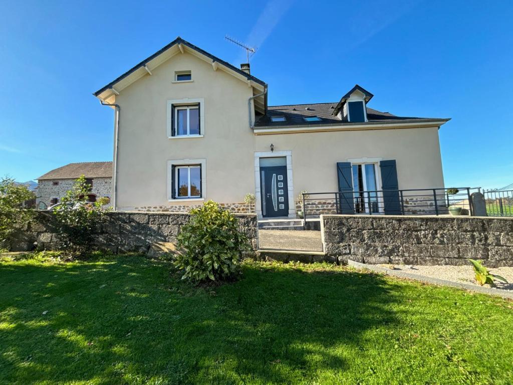 a large white house with a stone wall at Maison au cœur de notre ferme familiale in Asson
