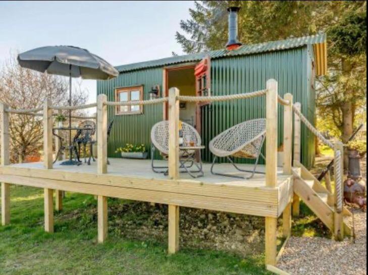 a wooden deck with chairs and an umbrella at Pooks Rest in Hurst Green