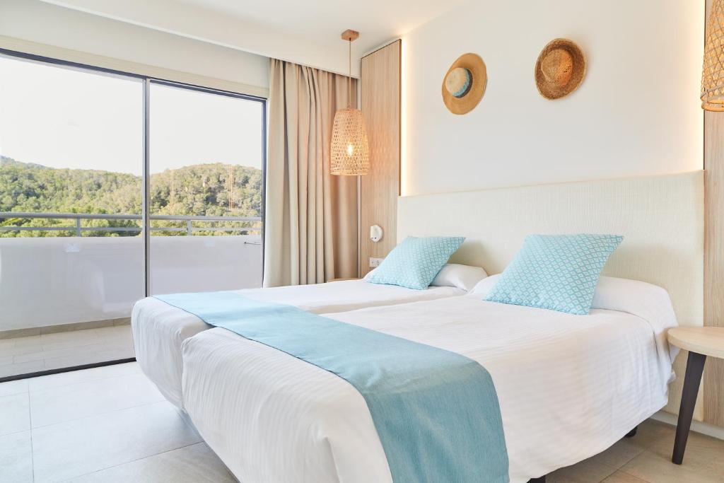 duas camas num quarto de hotel com uma grande janela em Apartamentos San Miguel Park & Esmeralda Mar em Puerto de San Miguel
