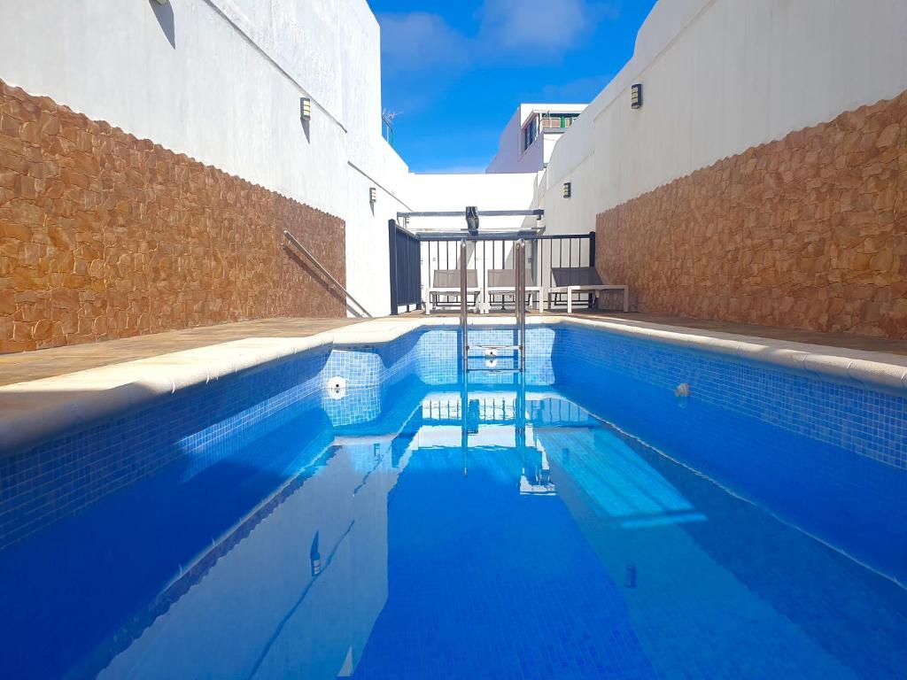 a swimming pool with blue water in front of a building at San Clemente with Pool & Wi-fi in Caleta de Interián