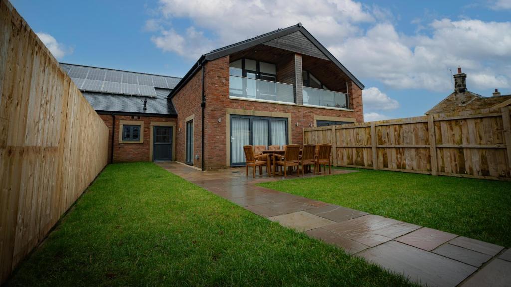 einen Hinterhof mit einem Tisch, Stühlen und einem Zaun in der Unterkunft Northumberland Luxury Stays - The Gavel in West Chevington