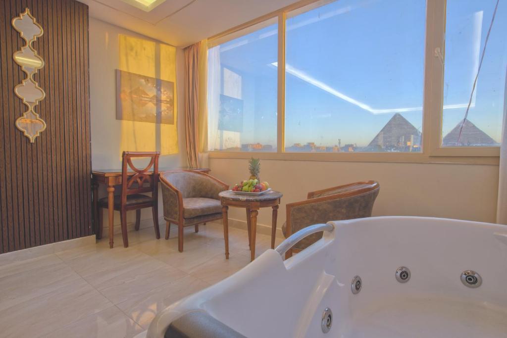 ein Bad mit einer Badewanne, einem Tisch und Stühlen in der Unterkunft The Muse Pyramids Inn Hotel in Kairo