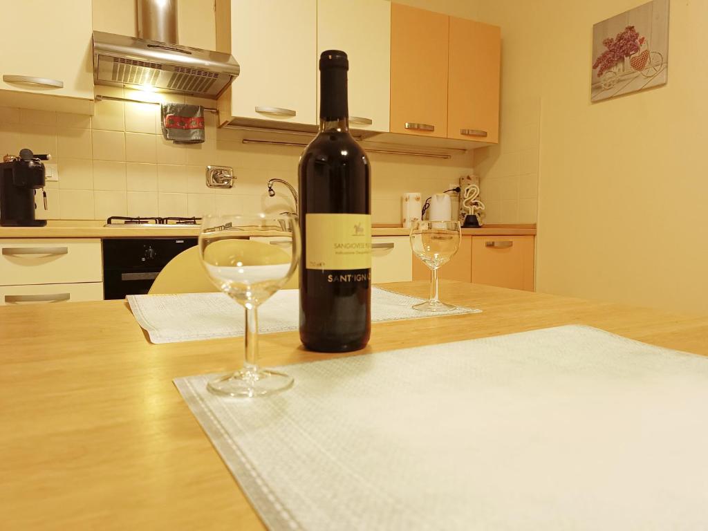 a bottle of wine sitting on a table with two glasses at Appartamento Gold Calcara in Calcara