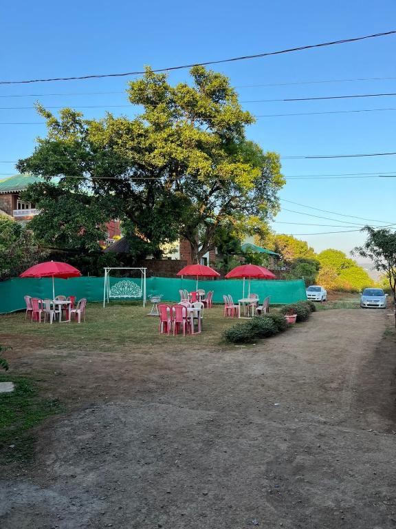 a group of tables with red umbrellas in a field at Swami Leela Relax Inn in Mahabaleshwar