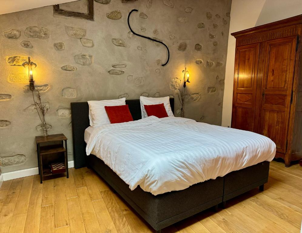 ein Schlafzimmer mit einem großen Bett mit zwei roten Kissen in der Unterkunft Pax et Amor Chambres d'hôtes de charme - Charming B&B in Mazerolles-du-Razès