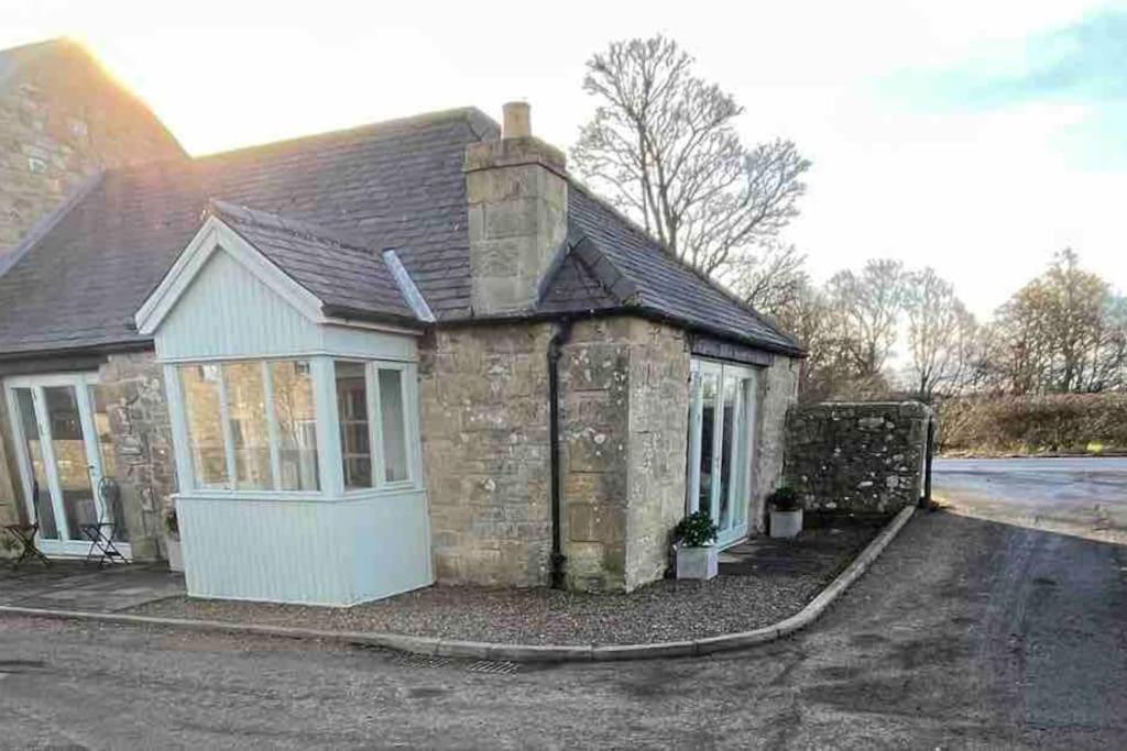 uma pequena casa de tijolos com uma entrada em West Lodge Cottage em Morpeth