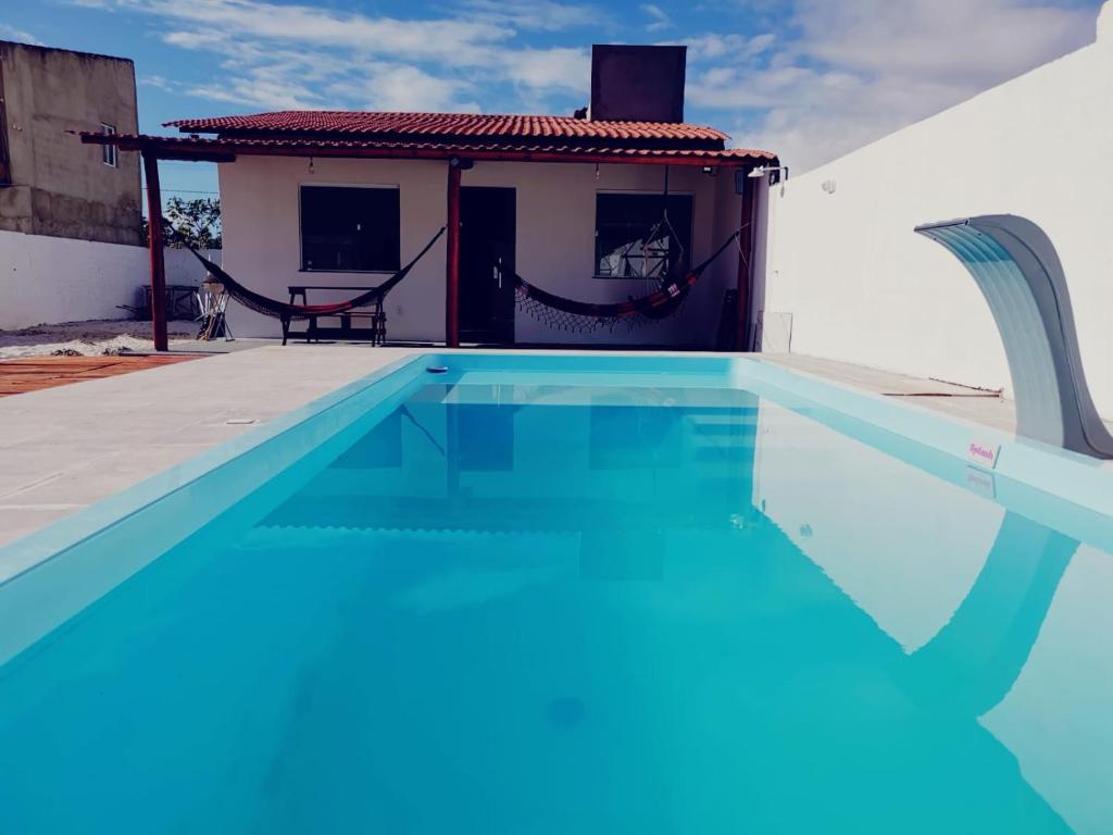 a swimming pool with blue water in front of a house at Casa de Praia Em Aracaju,Se in Barra dos Coqueiros
