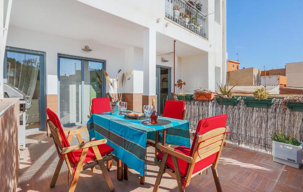 une table bleue avec des chaises rouges sur une terrasse dans l'établissement Amazing Apartment In Lorca With Kitchenette, à Lorca