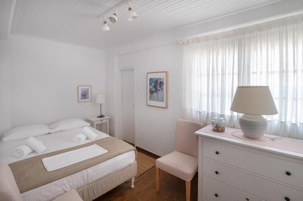- une chambre blanche avec un lit, un bureau et une chaise dans l'établissement Pouletis Family Villas Sea Apartments, à Kalamata