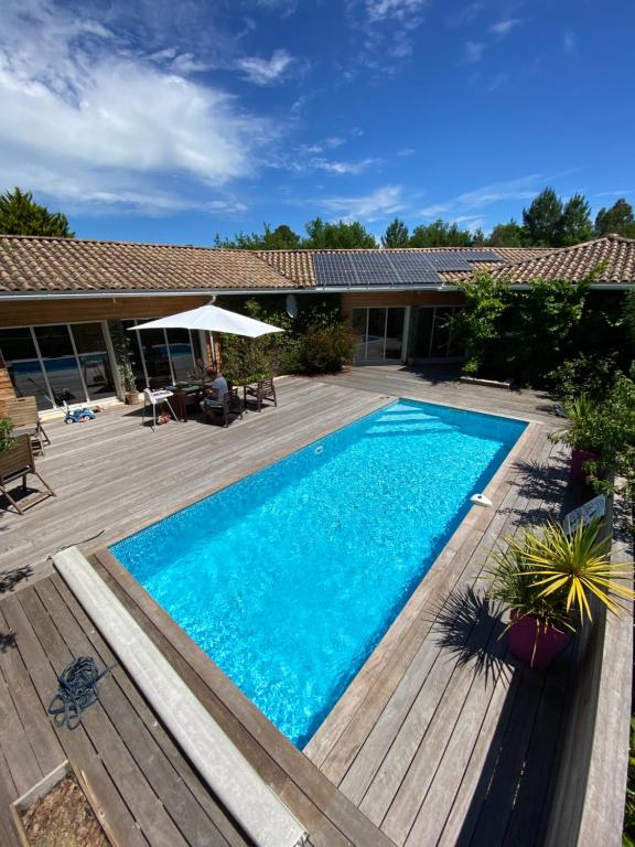 una piscina en un patio con terraza de madera en Villa entre lac et océan, en Biscarrosse