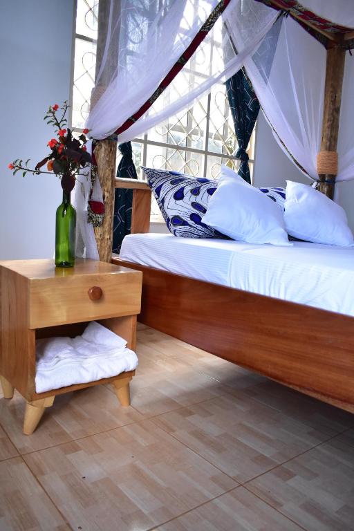 Kilimanjaro Accommodation في Msaranga: غرفة نوم بسرير وطاولة مع موقف ليلي