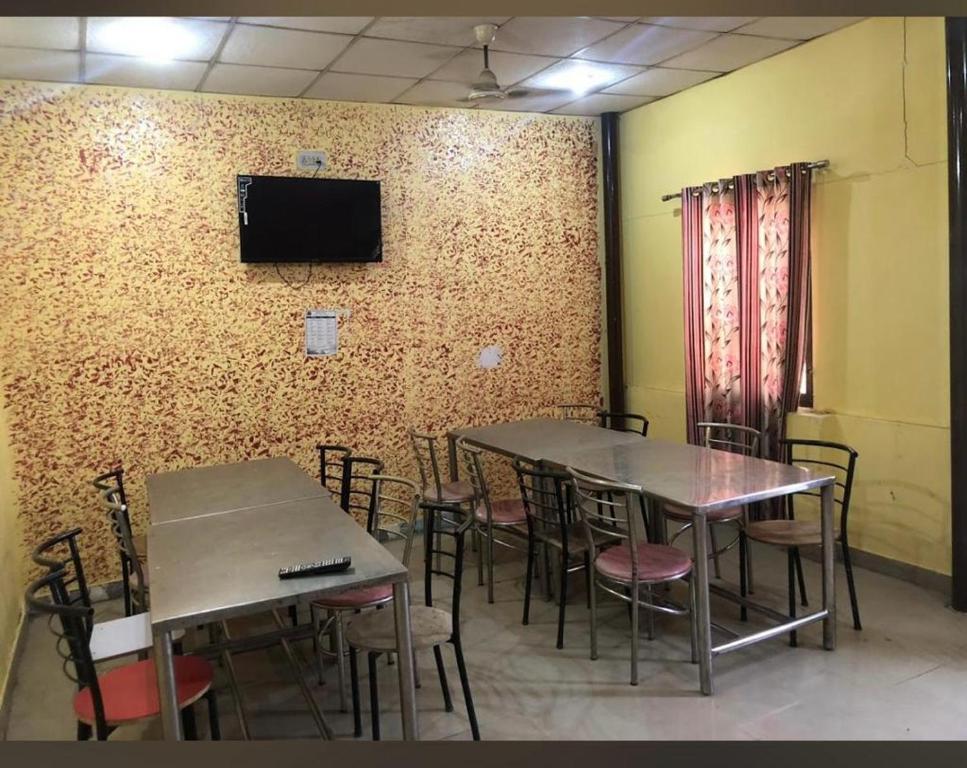 a room with two tables and chairs and a tv on a wall at Omjee Paying Guest in Dehradun