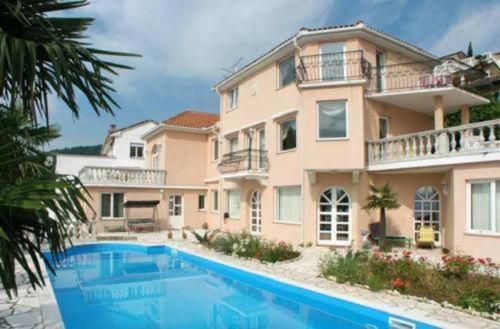 a large house with a swimming pool in front of it at Villa Palme 1 in Opatija
