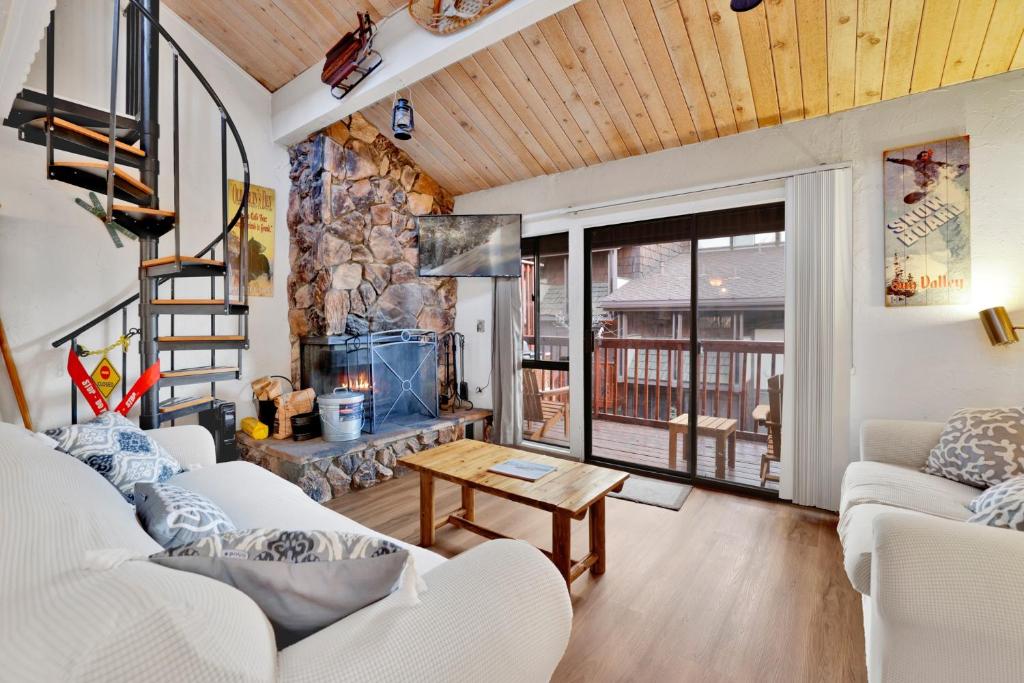 a living room with white furniture and a stone fireplace at 2354-Chairlift Lodge condo in Big Bear Lake
