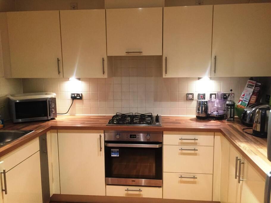 a kitchen with white cabinets and a stove top oven at 1 Bedroom Flat near Excel, O2, Canary Wharf - London in London