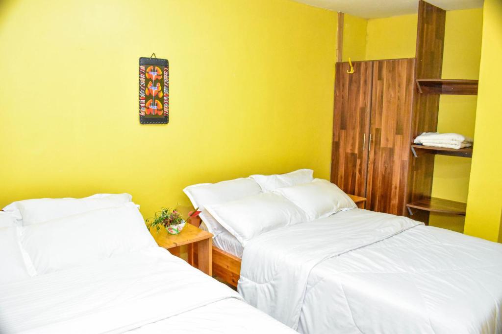 two beds in a room with yellow walls at Four seventy in Meru