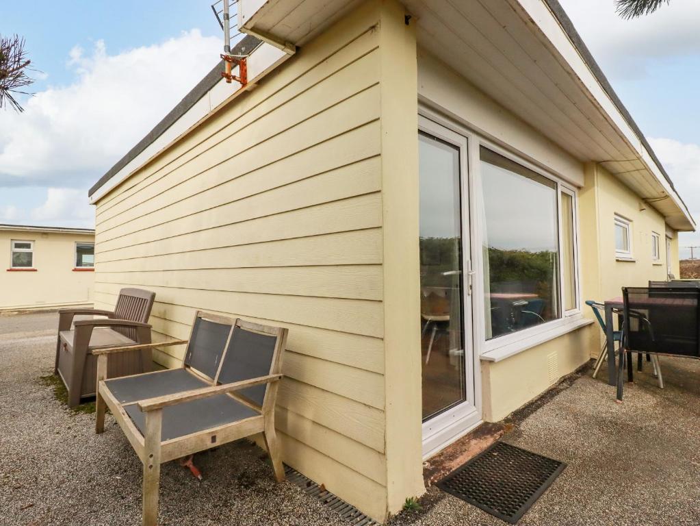 a house with two chairs and a table next to a window at Lapwing in Perranporth