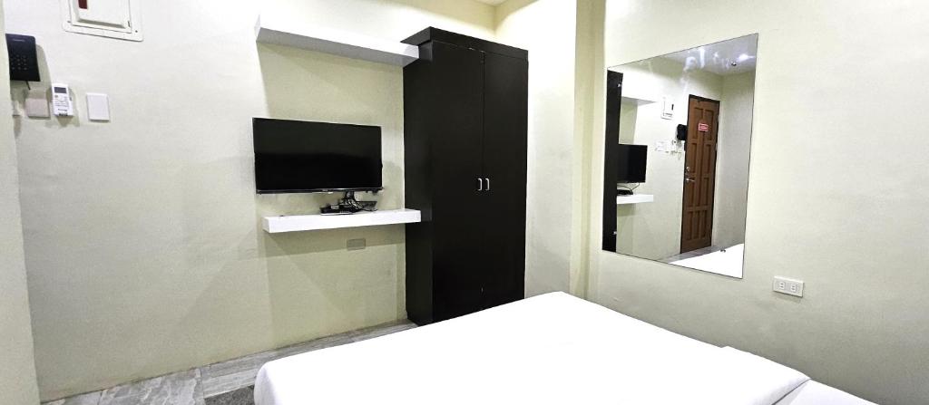 a room with a tv and a bed and a mirror at The JRJF Hotel near Tagum Terminal in Tagum