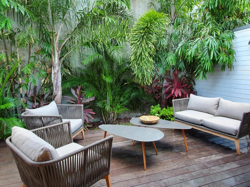un patio con sillas, un sofá y una mesa en Le Rocher Vert - Duplex climatisé pour 4, en Saint Barthelemy