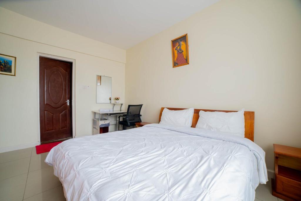 a bedroom with a white bed and a desk at Airport Vista Getaway-4km from jomo Kenyatta International Airport in Nairobi