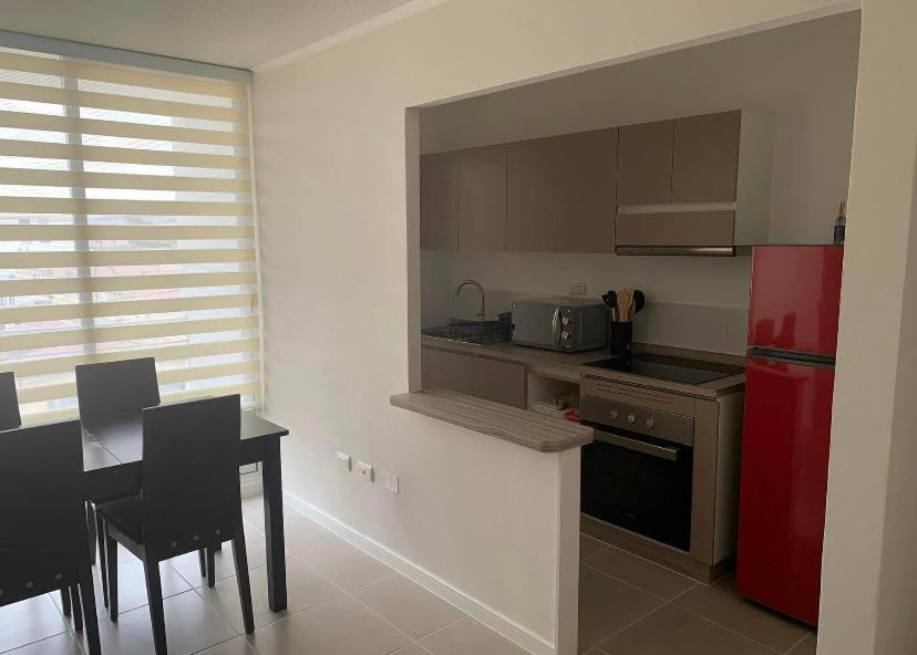 a kitchen with a red refrigerator and a table with chairs at Departamento Serena , La Florida in La Serena