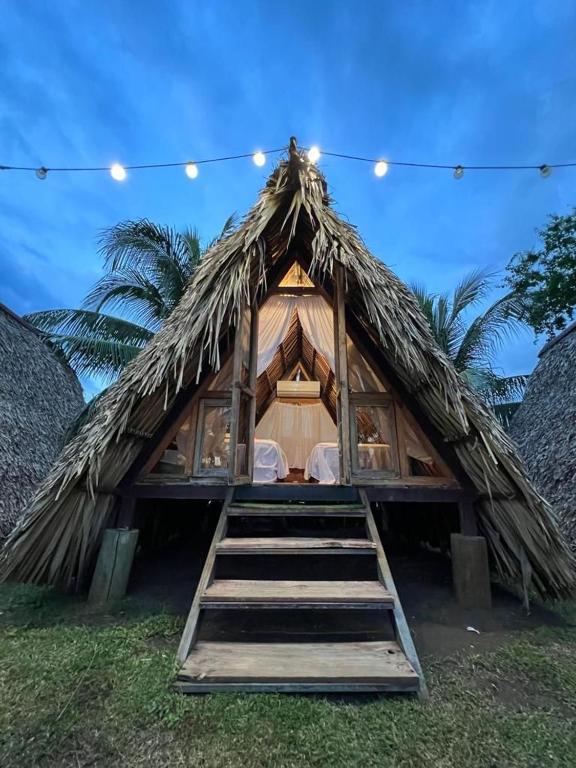 a thatch roof tent with a staircase leading to it at Playa Nautilus in Puerto San José