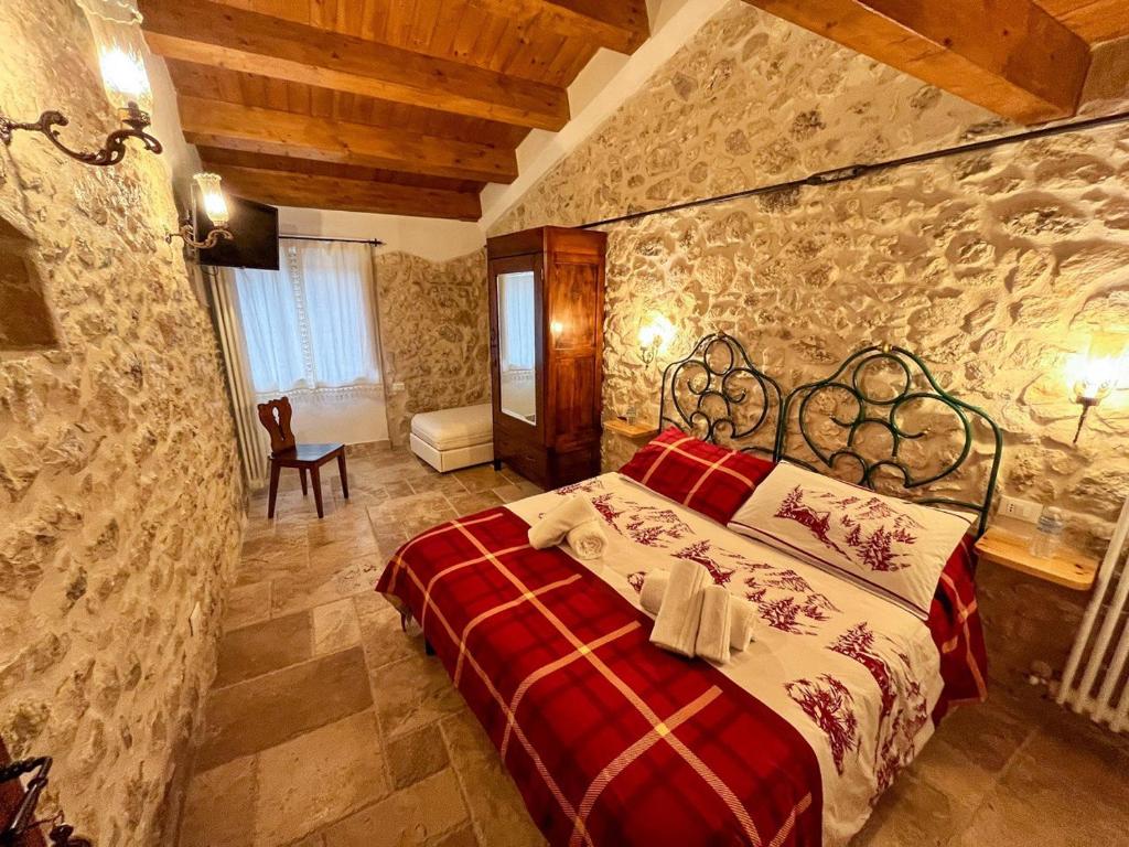 a bedroom with a red bed in a stone wall at B&B Casa Antonetti in Campo di Giove