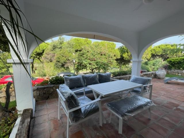 un patio con mesa, sillas y sofá en Casa Reserva Los Monteros en Marbella